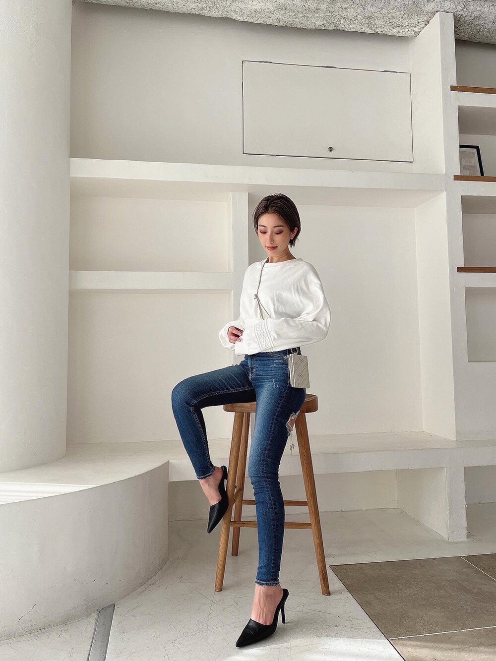 ホワイト系のスウェット、ブルー系のデニムパンツ、ブラック系のパンプスを着用したレディースの冬コーディネートの2枚目の写真