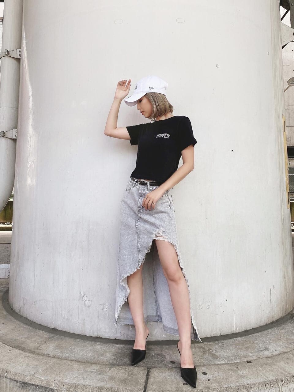 グレー系のデニムスカート、ブラック系のTシャツ/カットソー、ブラック系のパンプスを着用したレディースの夏コーディネートの3枚目の写真