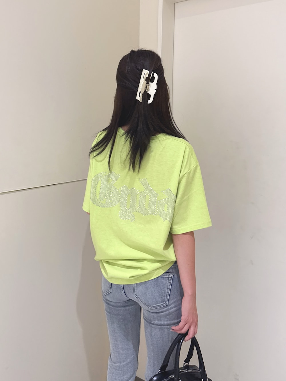 ブルー系のデニムパンツ、ブラック系のサンダル、ブラック系のハンドバッグを着用したレディースの夏コーディネートの5枚目の写真