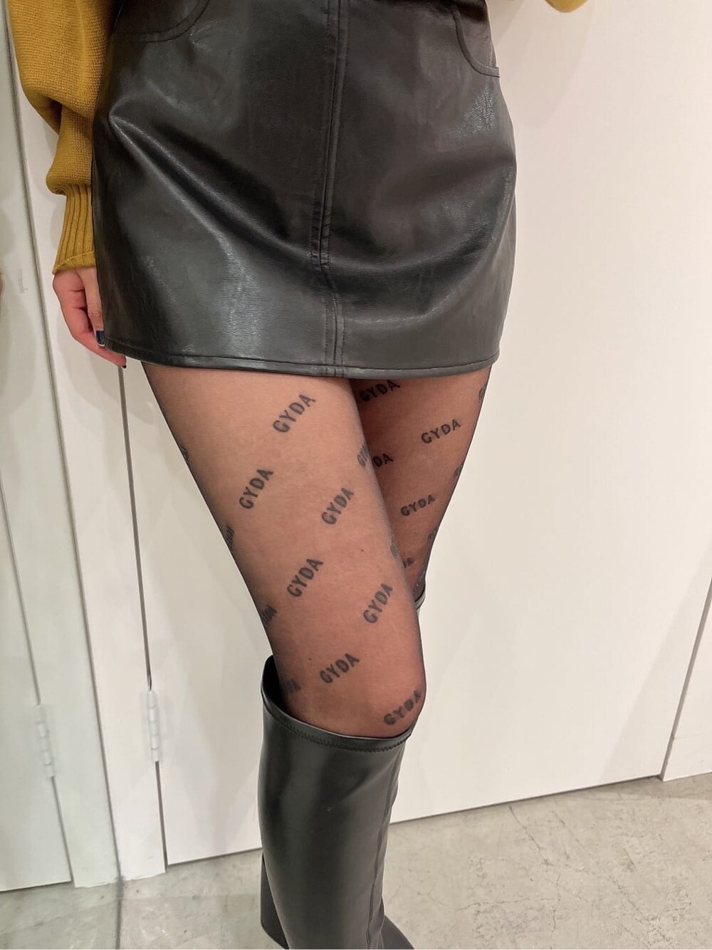 ブラック系のブーツ、イエロー系のニット/セーター、ブラック系のスカートを着用したレディースの秋コーディネートの6枚目の写真