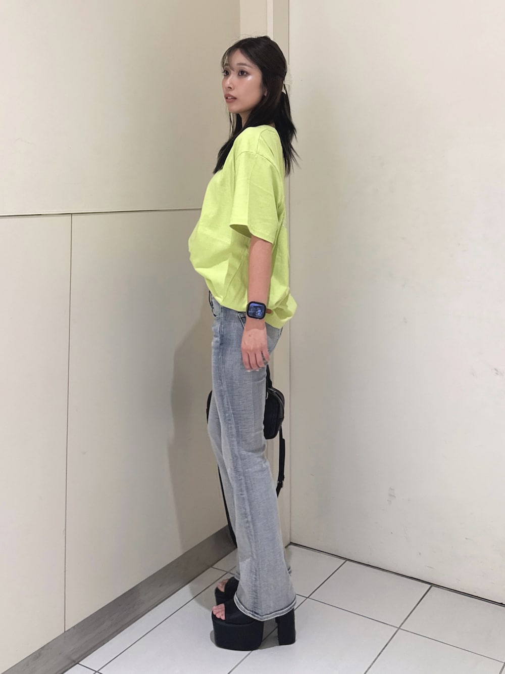 ブルー系のデニムパンツ、ブラック系のサンダル、ブラック系のハンドバッグを着用したレディースの夏コーディネートの2枚目の写真