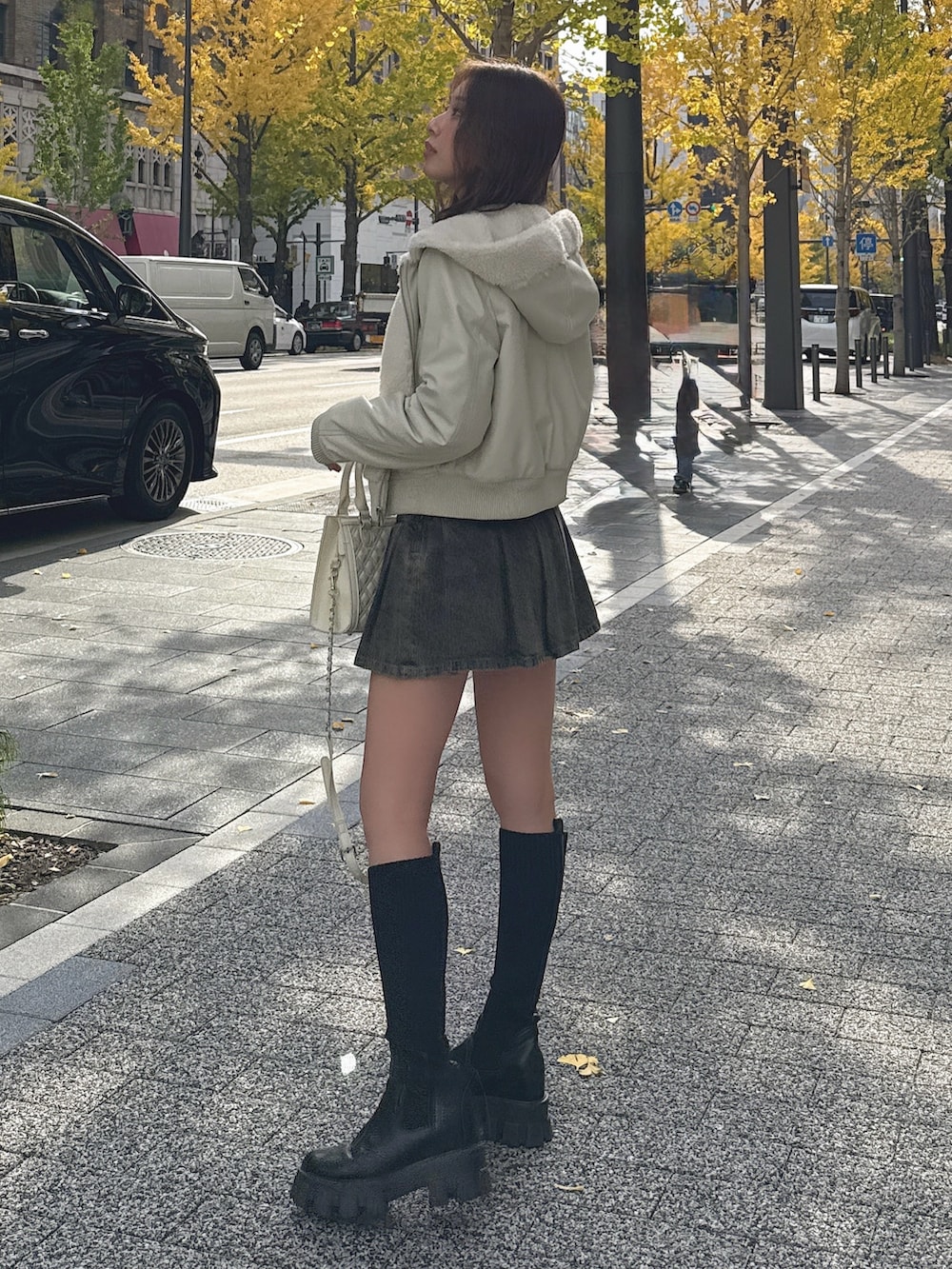 ブルー系のデニムスカート、ホワイト系のダウンジャケット/コート、ブラック系のブーツを着用したレディースの冬コーディネートの3枚目の写真