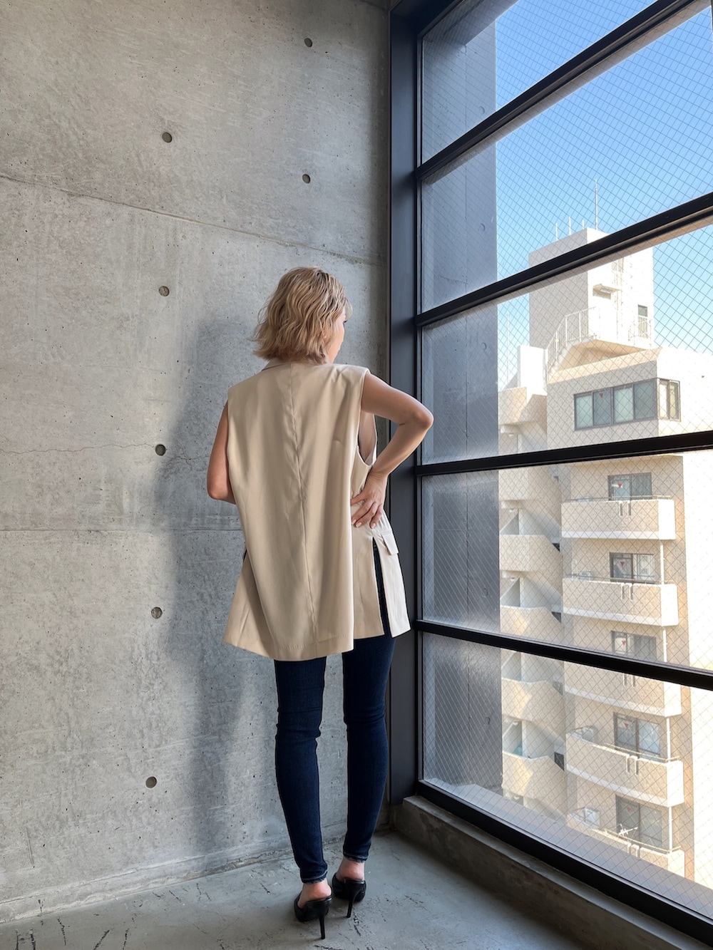 ホワイト系のニット/セーター、ブルー系のデニムパンツ、ホワイト系のテーラードジャケットを着用したレディースの夏コーディネートの3枚目の写真