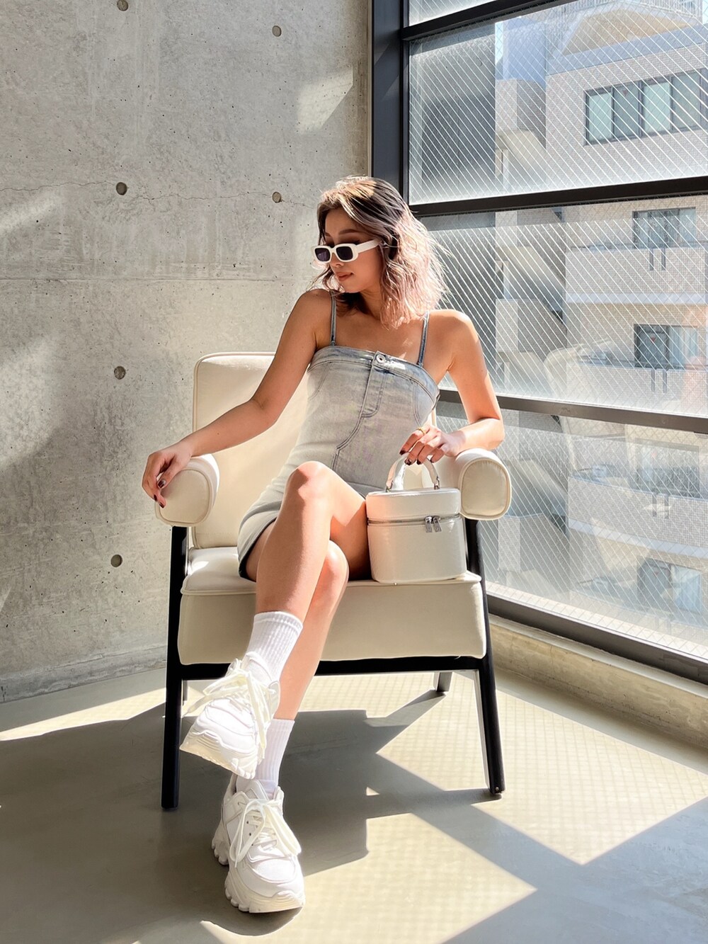 ブルー系のワンピース、ブラック系のハンドバッグ、ホワイト系のサングラスを着用したレディースの春コーディネートの2枚目の写真