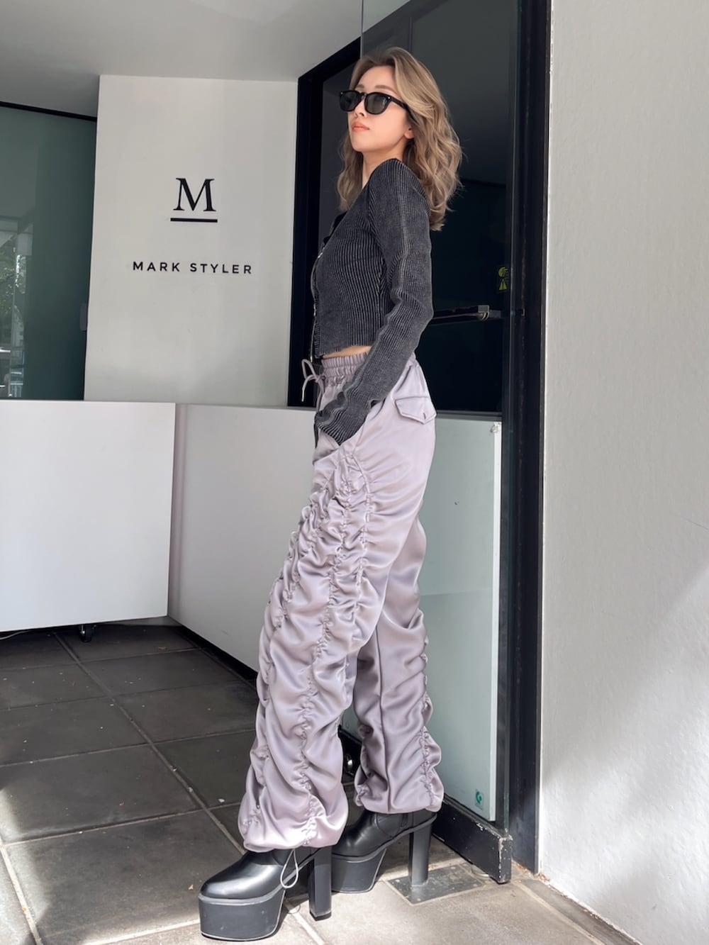 グレー系のその他パンツ、ブラック系のニット/セーター、ブラック系のブーツを着用したレディースの秋コーディネートの2枚目の写真