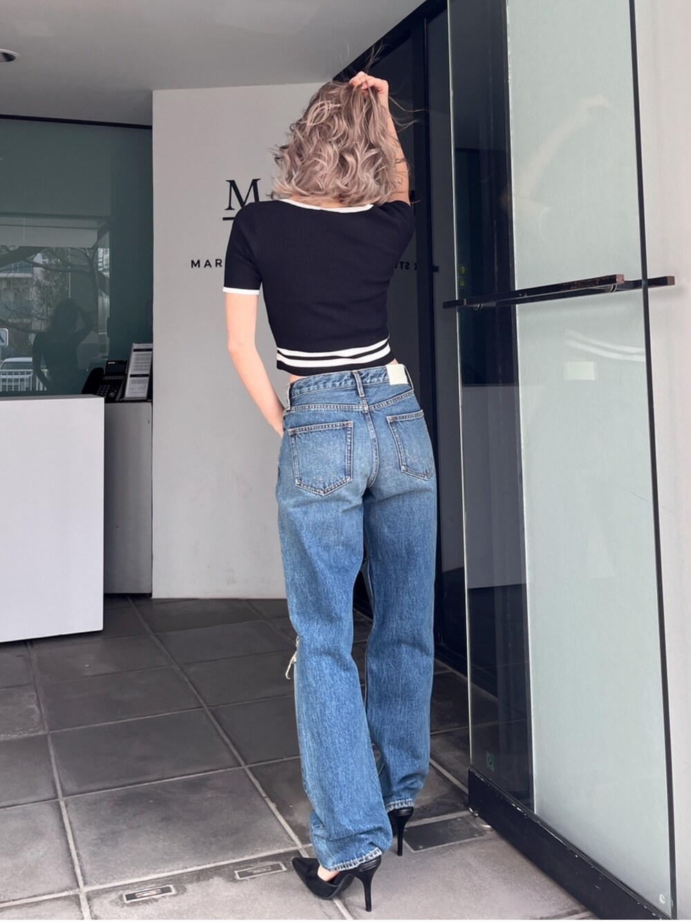 ブルー系のデニムパンツ、ブラック系のニット/セーターを着用したレディースの秋コーディネートの2枚目の写真