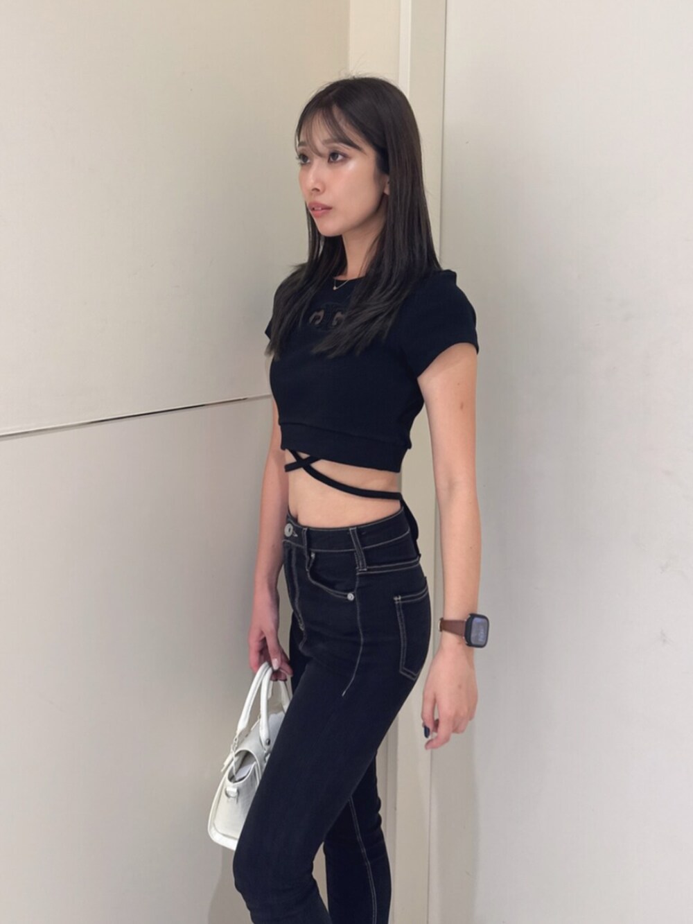 ブラック系のサンダル、ブラック系のハンドバッグ、ブラック系のデニムパンツを着用したレディースの夏コーディネートの5枚目の写真