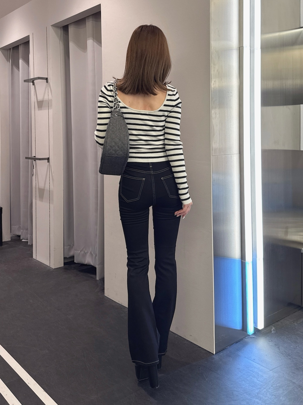 ブラック系のデニムパンツ、ブラック系のブーツ、その他のニット/セーターを着用したレディースの秋コーディネートの2枚目の写真