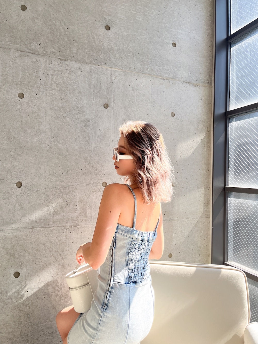 ブルー系のワンピース、ブラック系のハンドバッグ、ホワイト系のサングラスを着用したレディースの春コーディネートの4枚目の写真