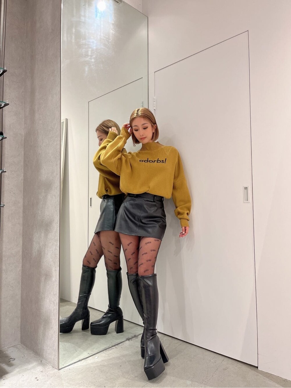 ブラック系のブーツ、イエロー系のニット/セーター、ブラック系のスカートを着用したレディースの秋コーディネートの3枚目の写真