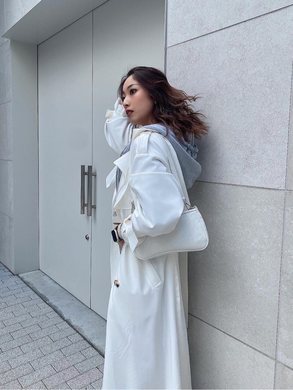 ブラック系のパンプス、ホワイト系のトレンチコート、ホワイト系のニット/セーターを着用したレディースの冬コーディネートの5枚目の写真