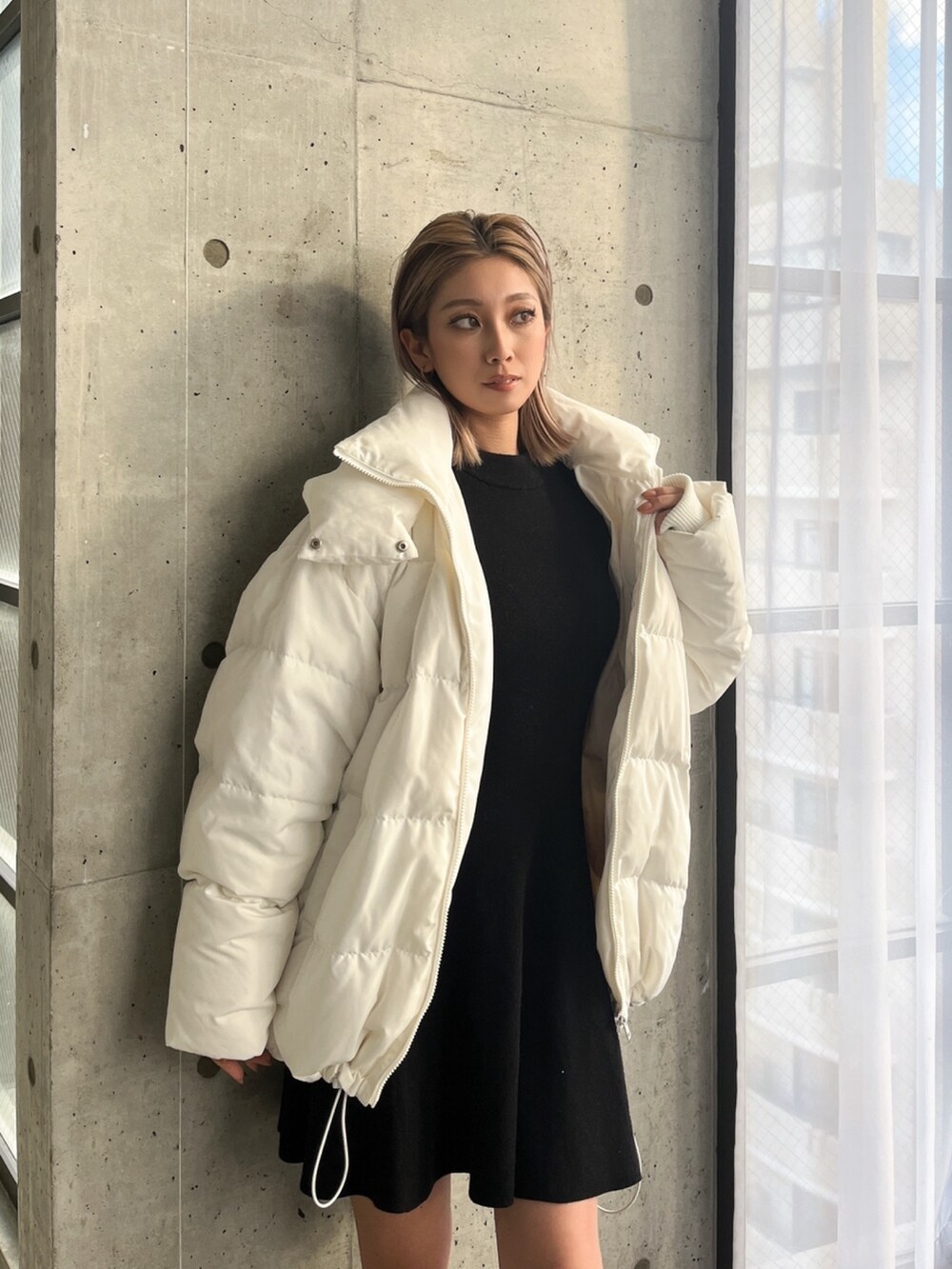 ブラック系のワンピース、ブラック系のブーツ、ホワイト系のダウンジャケット/コートを着用したレディースの冬コーディネートの3枚目の写真