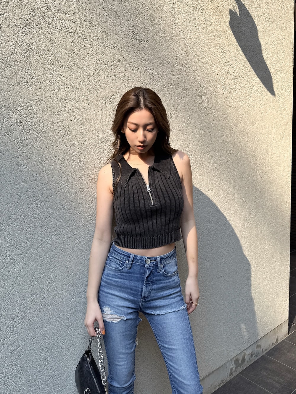 ブラック系のニット/セーター、ブルー系のデニムパンツを着用したレディースの春コーディネートの3枚目の写真