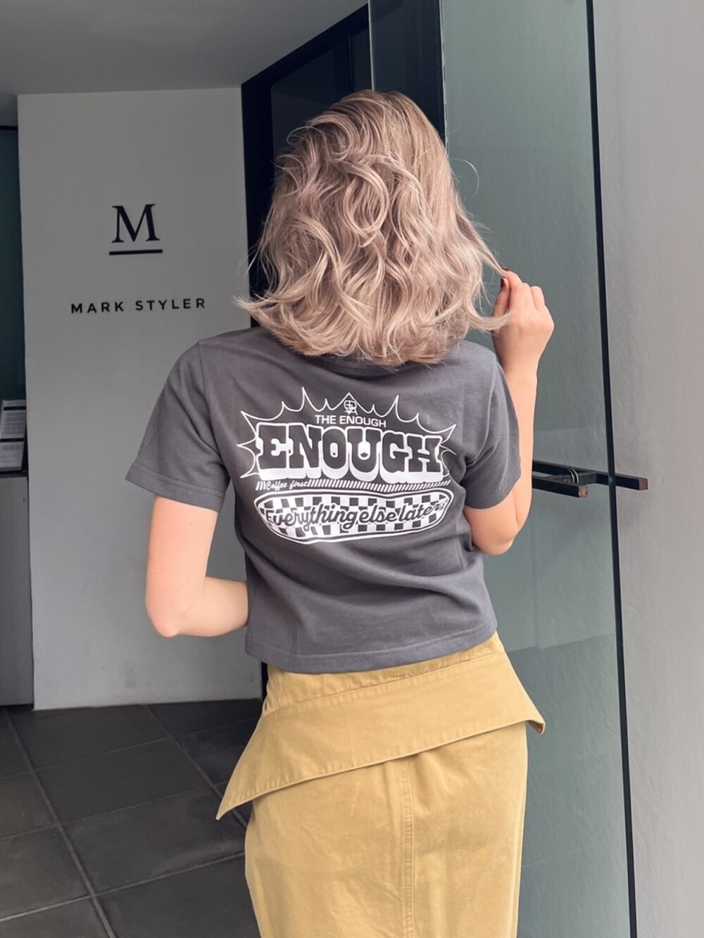 グレー系のTシャツ/カットソー、グリーン系のスカート、ブラック系のサンダルを着用したレディースの秋コーディネートの6枚目の写真