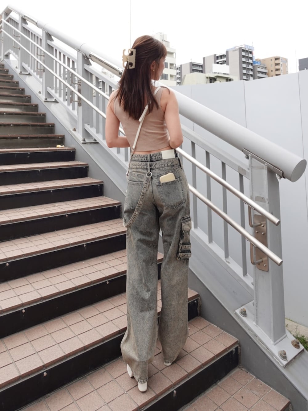 ベージュ系のキャミソール、ブルー系のデニムパンツ、ホワイト系のサンダルを着用したレディースの夏コーディネートの4枚目の写真
