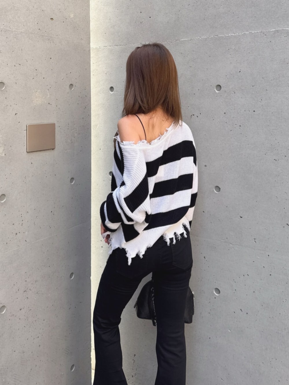 ブラック系のデニムパンツ、ブラック系のブーツ、ホワイト系のハンドバッグを着用したレディースの秋コーディネートの8枚目の写真