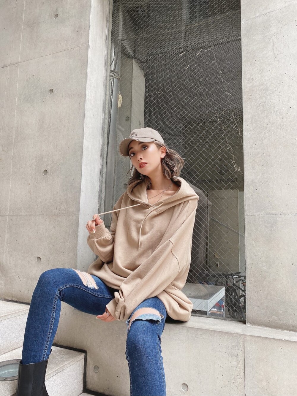 ブルー系のデニムパンツ、ベージュ系のパーカー、ベージュ系のキャップを着用したレディースの秋コーディネートの7枚目の写真