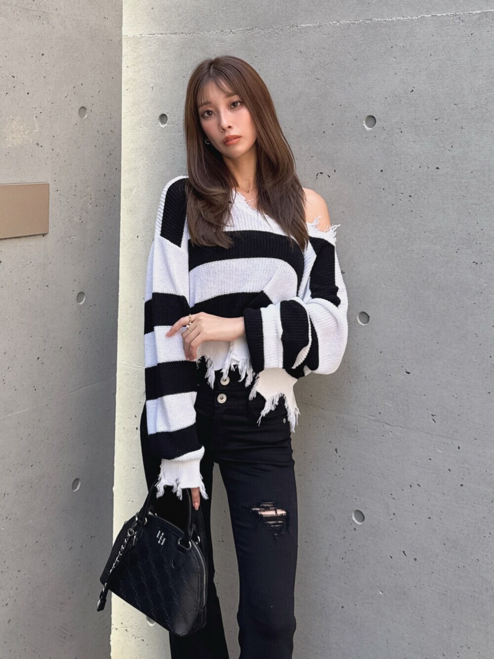 ブラック系のデニムパンツ、ブラック系のブーツ、ホワイト系のハンドバッグを着用したレディースの秋コーディネートの5枚目の写真