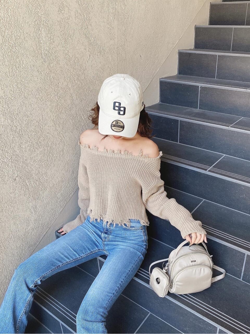 ブルー系のデニムパンツ、ベージュ系のニット/セーター、ホワイト系のキャップを着用したレディースの冬コーディネートの6枚目の写真