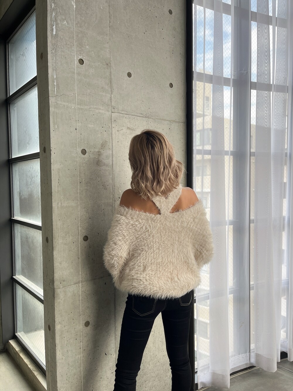 ホワイト系のニット/セーター、ブラック系のデニムパンツ、ブラック系のブーツを着用したレディースの秋コーディネートの2枚目の写真