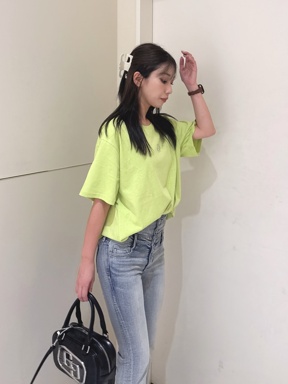 ブルー系のデニムパンツ、ブラック系のサンダル、ブラック系のハンドバッグを着用したレディースの夏コーディネートの6枚目の写真