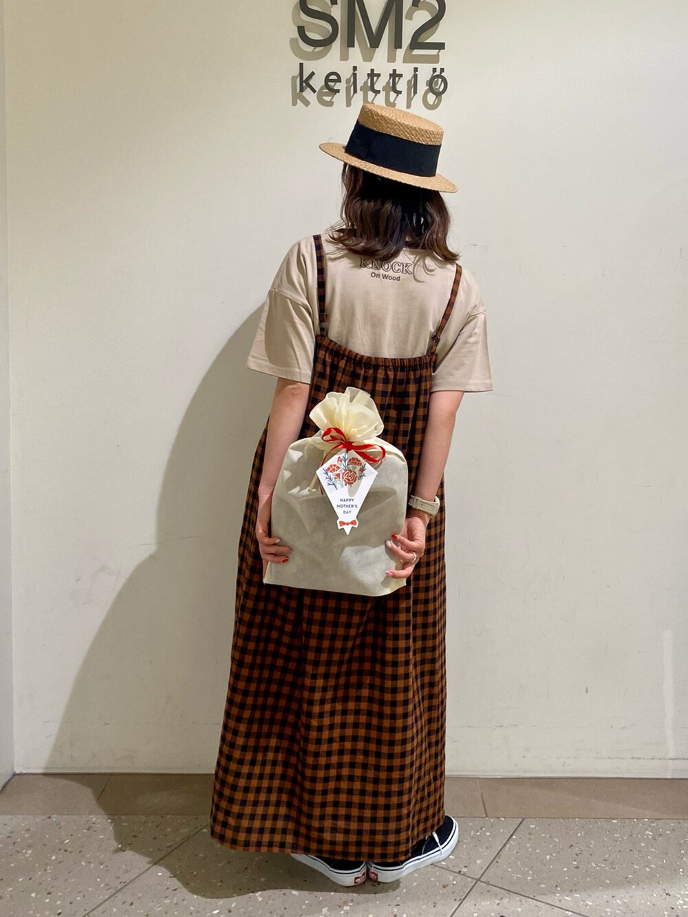 ベージュ系のTシャツ/カットソー、ブラウン系のワンピース、ブラック系のスニーカーを着用したレディースの春コーディネートの2枚目の写真