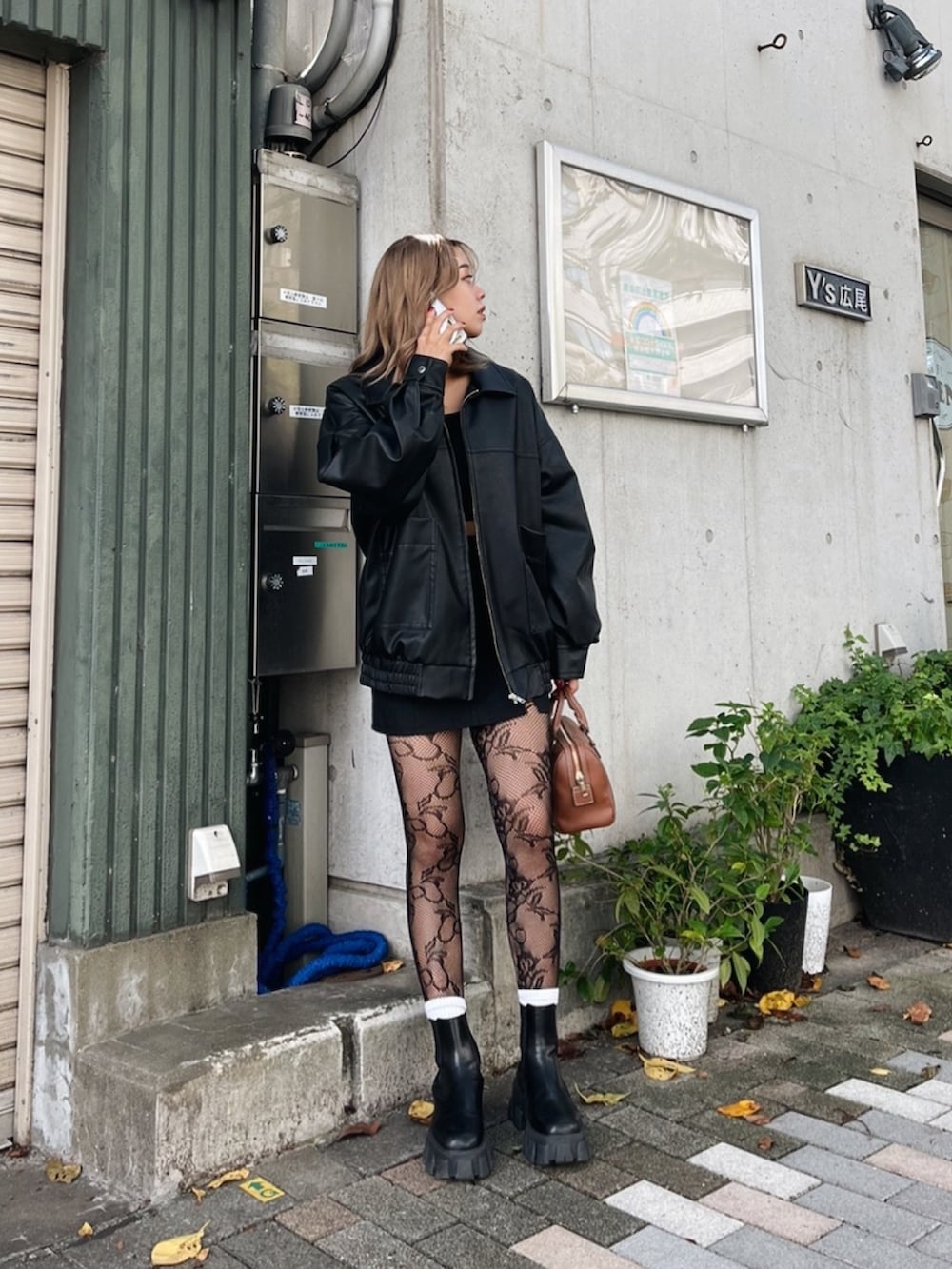 ブラック系のブルゾン、ブラック系のブーツ、ブラウン系のボストンバッグを着用したレディースの秋コーディネートの2枚目の写真