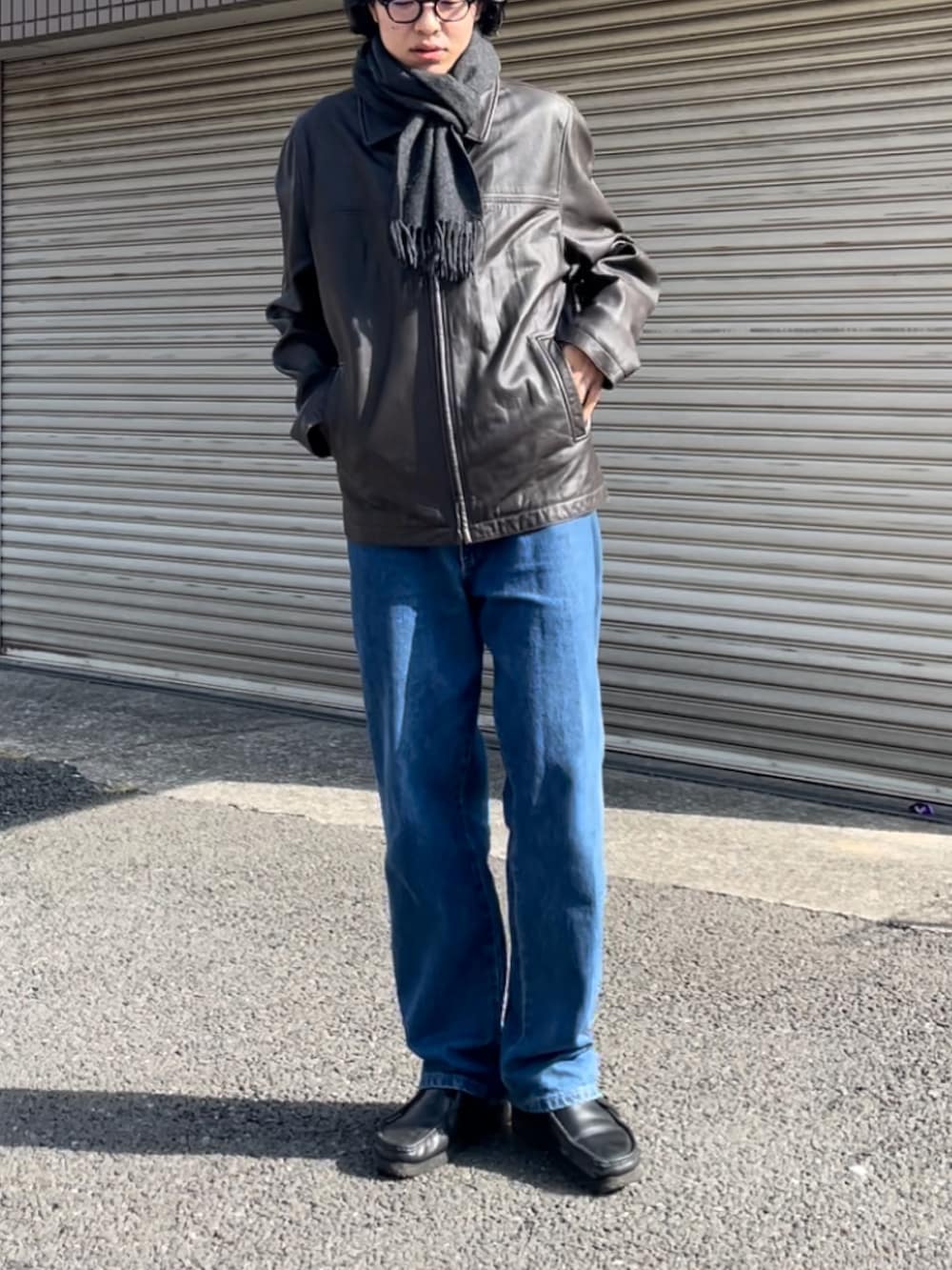 ブラウン系のライダースジャケット、ホワイト系のTシャツ/カットソー、ブルー系のデニムパンツを着用したメンズの秋コーディネートの2枚目の写真