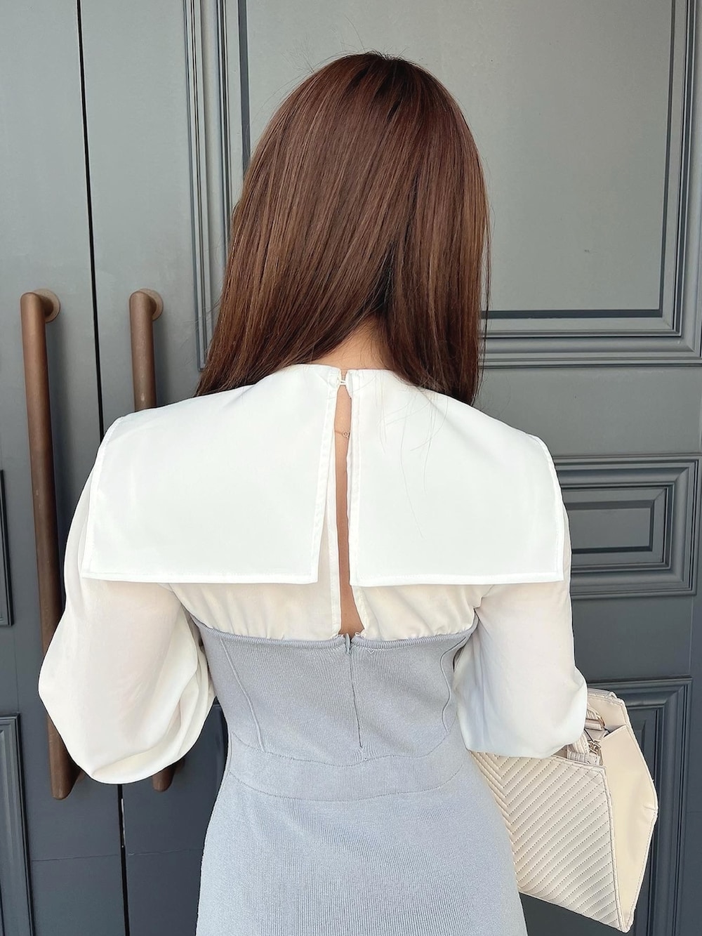 ブルー系のワンピース、ホワイト系のハンドバッグ、ホワイト系のパンプスを着用したレディースの冬コーディネートの3枚目の写真