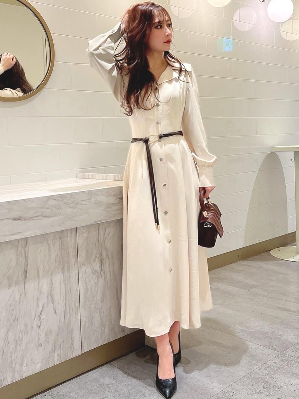 ホワイト系のワンピース、ブラウン系のハンドバッグ、ブラウン系のベルトを着用したレディースの冬コーディネートの3枚目の写真