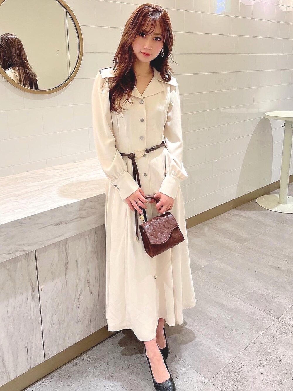 ホワイト系のワンピース、ブラウン系のハンドバッグ、ブラウン系のベルトを着用したレディースの冬コーディネートの2枚目の写真