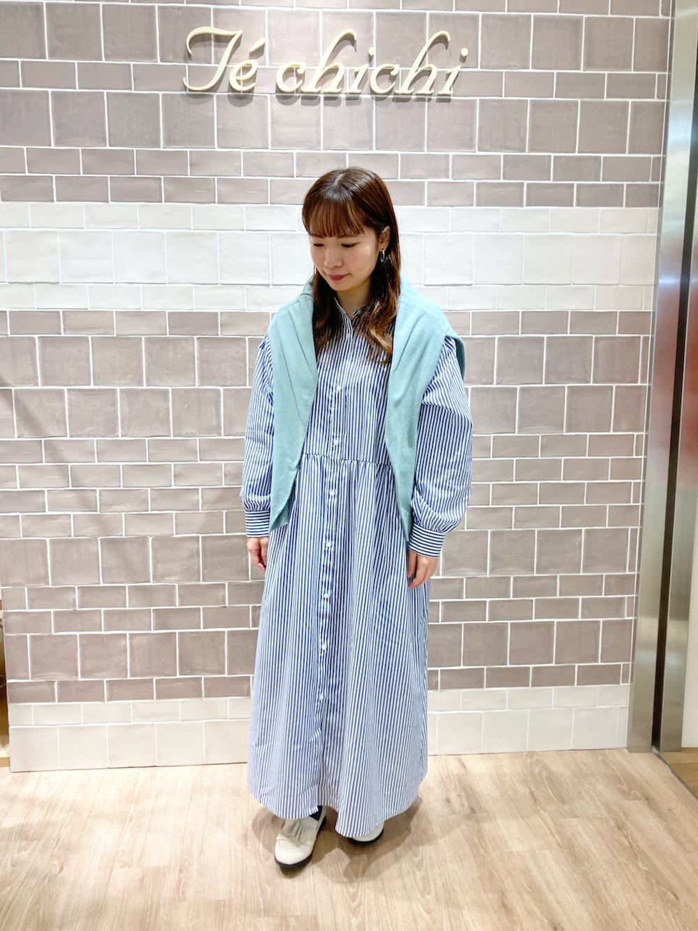 ブルー系のワンピース、グリーン系のカーディガン/ボレロ、ベージュ系のローファーを着用したレディースの冬コーディネートの2枚目の写真