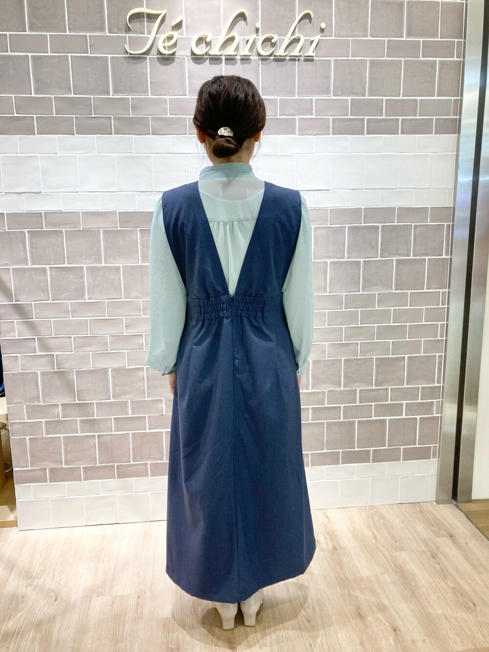 グリーン系のシャツ/ブラウス、ブルー系のジャンパースカート、ベージュ系のドレスシューズを着用したレディースの春コーディネートの3枚目の写真