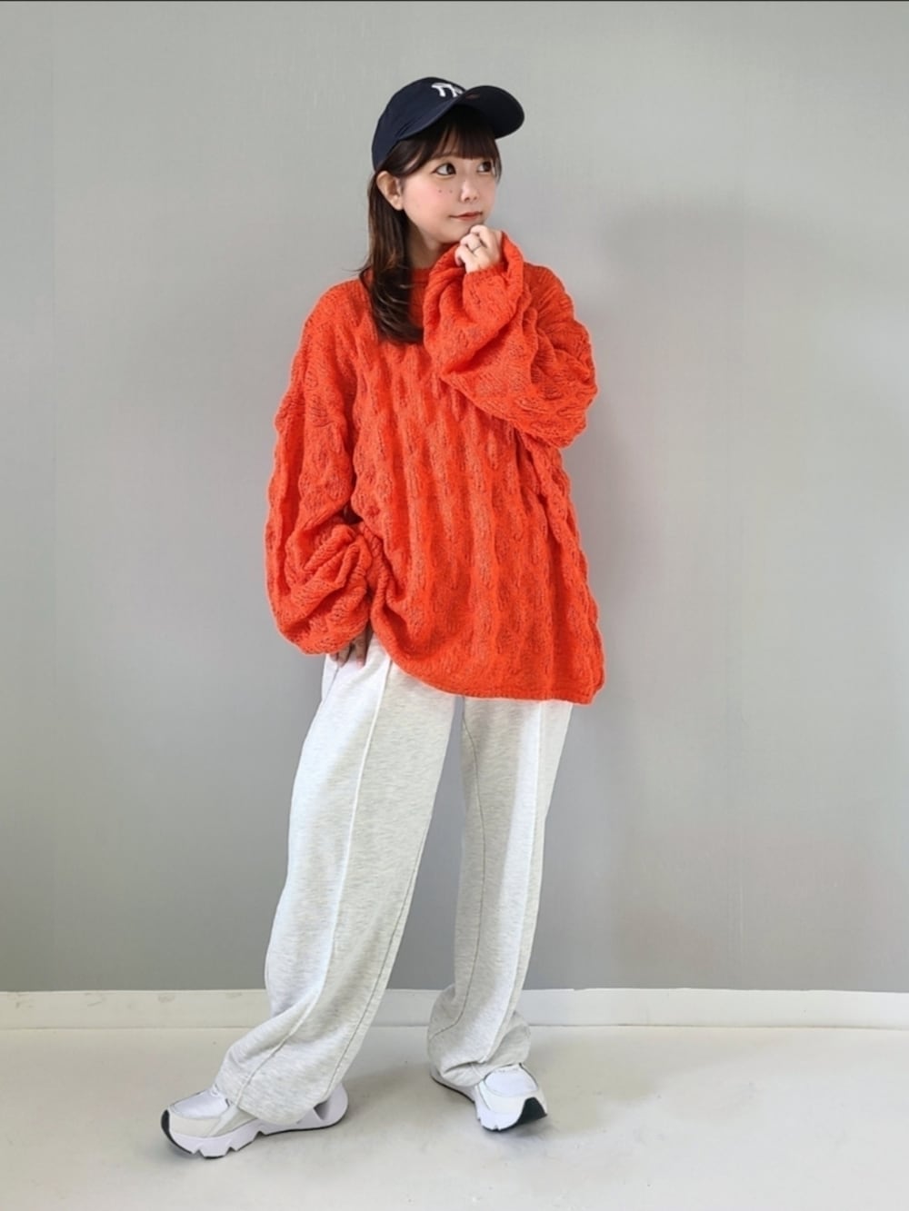 オレンジ系のニット/セーター、ベージュ系のスウェットパンツ、ホワイト系のスニーカーを着用したレディースの秋コーディネートの2枚目の写真