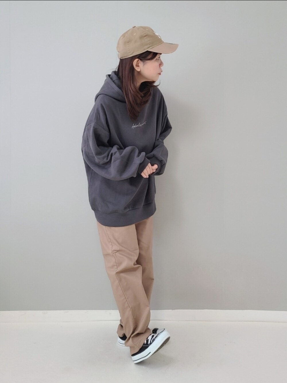 グレー系のパーカー、ベージュ系のパンツ、ブラック系のスニーカーを着用したレディースの秋コーディネートの3枚目の写真