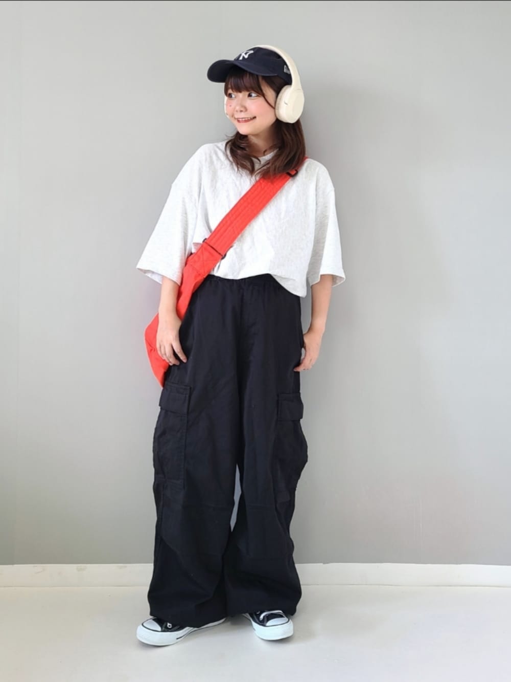 グレー系のトップス、ブラック系のカーゴパンツ、オレンジ系のショルダーバッグを着用したレディースの夏コーディネートの2枚目の写真