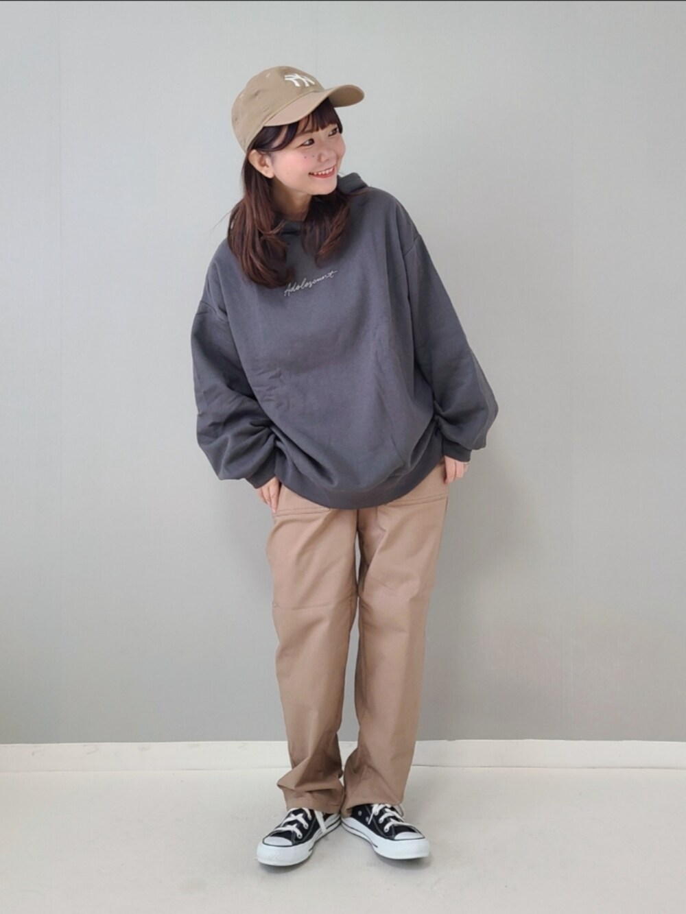 グレー系のパーカー、ベージュ系のパンツ、ブラック系のスニーカーを着用したレディースの秋コーディネートの2枚目の写真