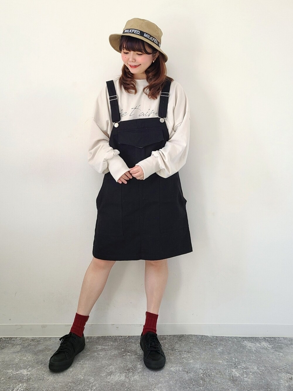 ブラック系のジャンパースカート、ホワイト系のスウェット、ブラック系のスニーカーを着用したレディースの春コーディネートの2枚目の写真