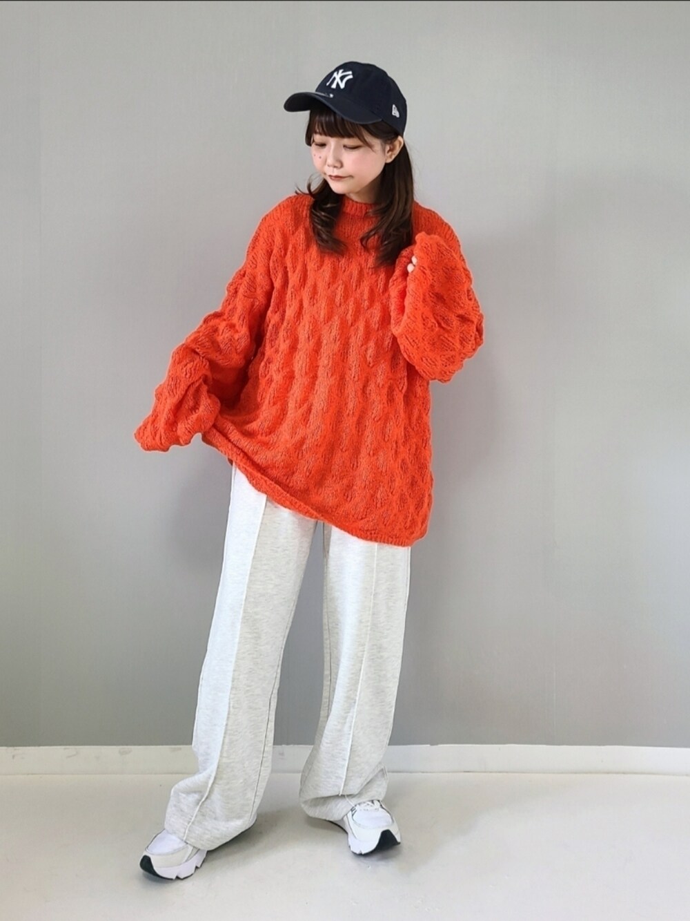 オレンジ系のニット/セーター、ベージュ系のスウェットパンツ、ホワイト系のスニーカーを着用したレディースの秋コーディネートの3枚目の写真