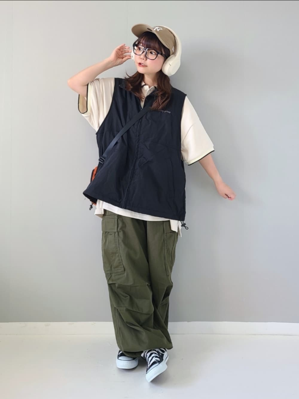 ブラック系のベスト、ホワイト系のポロシャツ、オレンジ系のショルダーバッグを着用したレディースの夏コーディネートの4枚目の写真