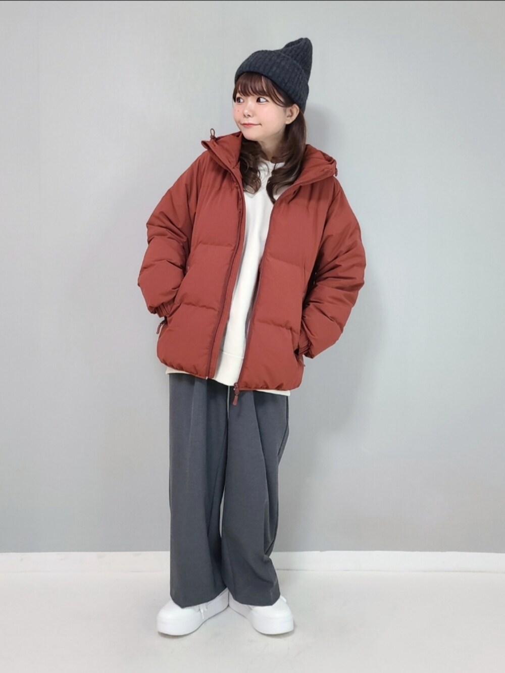 オレンジ系のダウンジャケット/コート、ホワイト系のスウェット、グレー系のパンツを着用したレディースの冬コーディネートの4枚目の写真