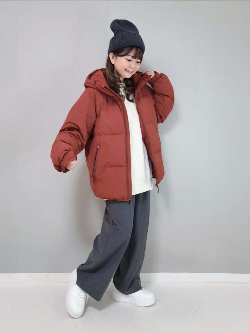 オレンジ系のダウンジャケット/コート、ホワイト系のスウェット、グレー系のパンツを着用したレディースの冬コーディネートの3枚目の写真