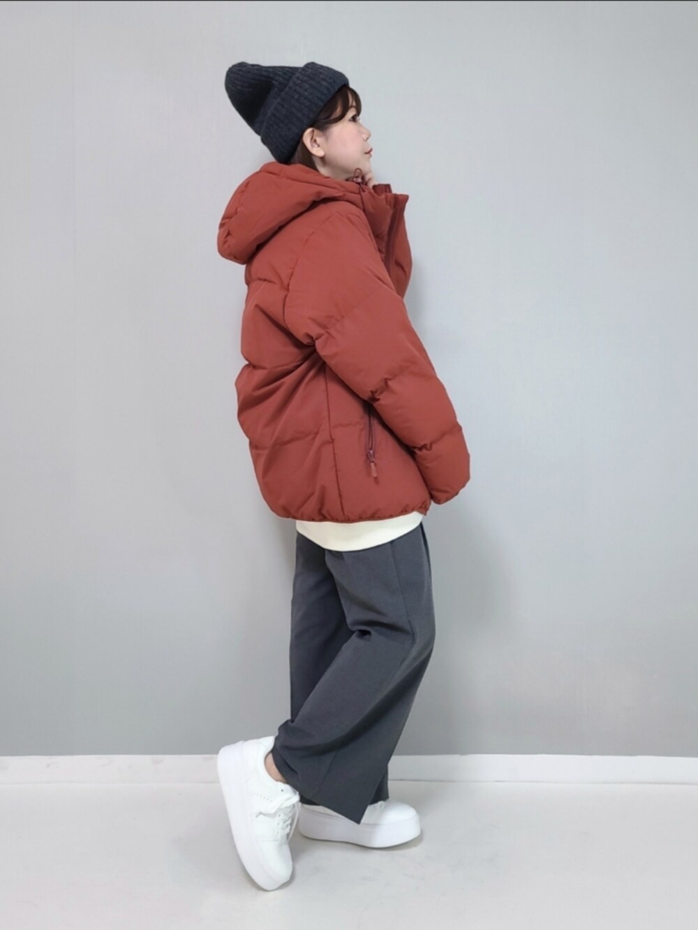 オレンジ系のダウンジャケット/コート、ホワイト系のスウェット、グレー系のパンツを着用したレディースの冬コーディネートの5枚目の写真