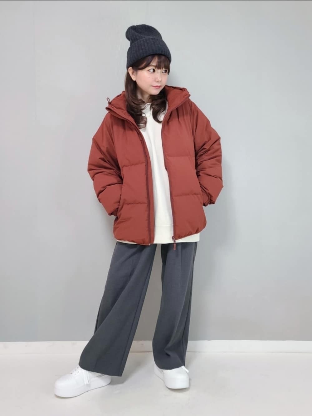 オレンジ系のダウンジャケット/コート、ホワイト系のスウェット、グレー系のパンツを着用したレディースの冬コーディネートの2枚目の写真