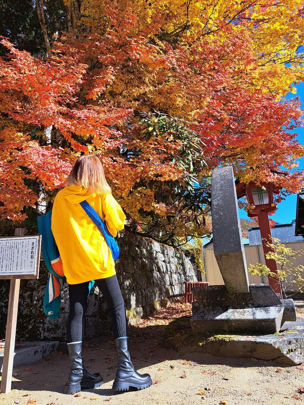 ブラック系のその他パンツ、ブラック系のブーツ、ブルー系のショルダーバッグを着用したレディースの秋コーディネートの2枚目の写真