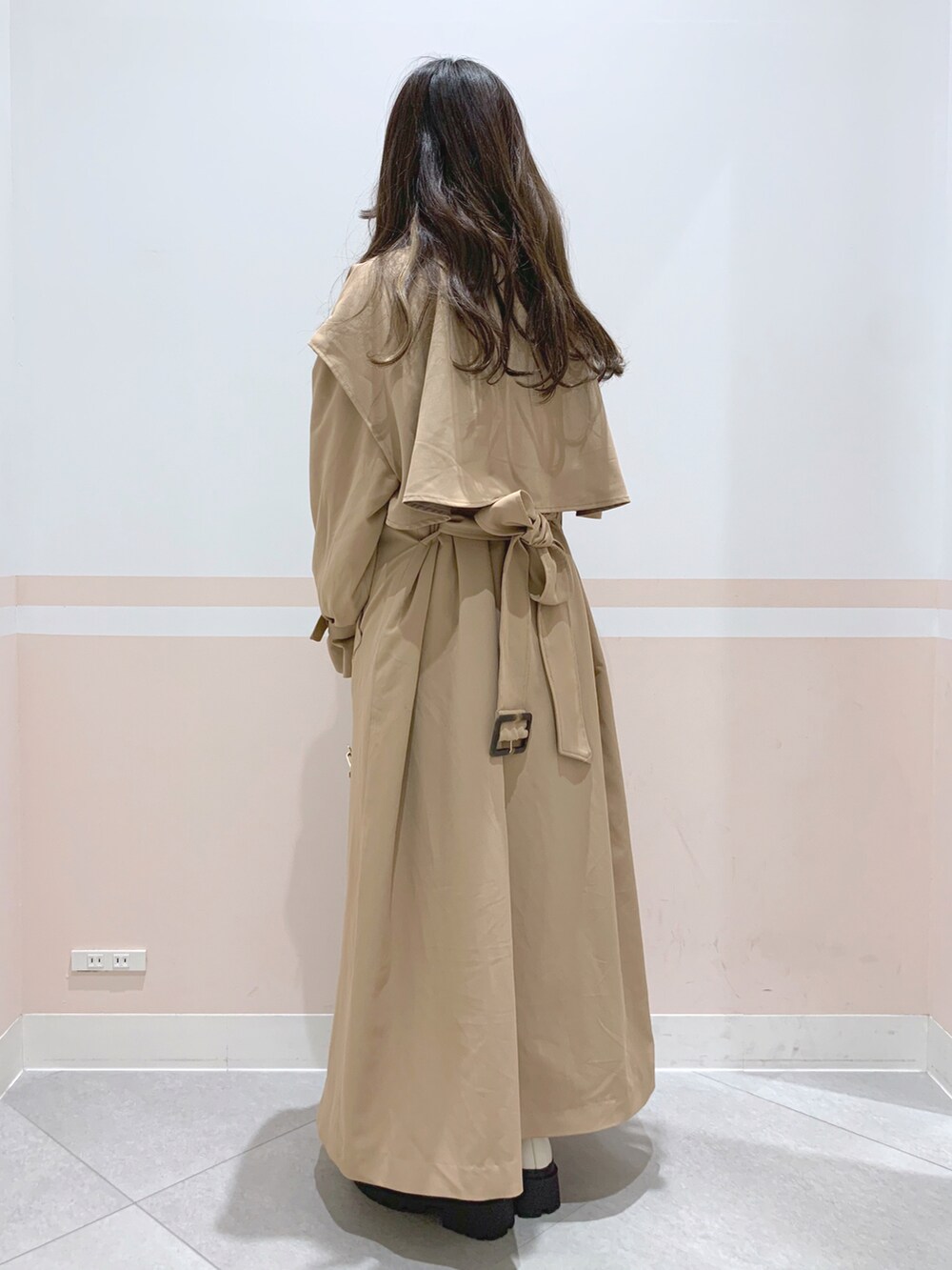 イエロー系のトレンチコート、ブラウン系のボストンバッグ、ホワイト系のブーツを着用したレディースの冬コーディネートの2枚目の写真