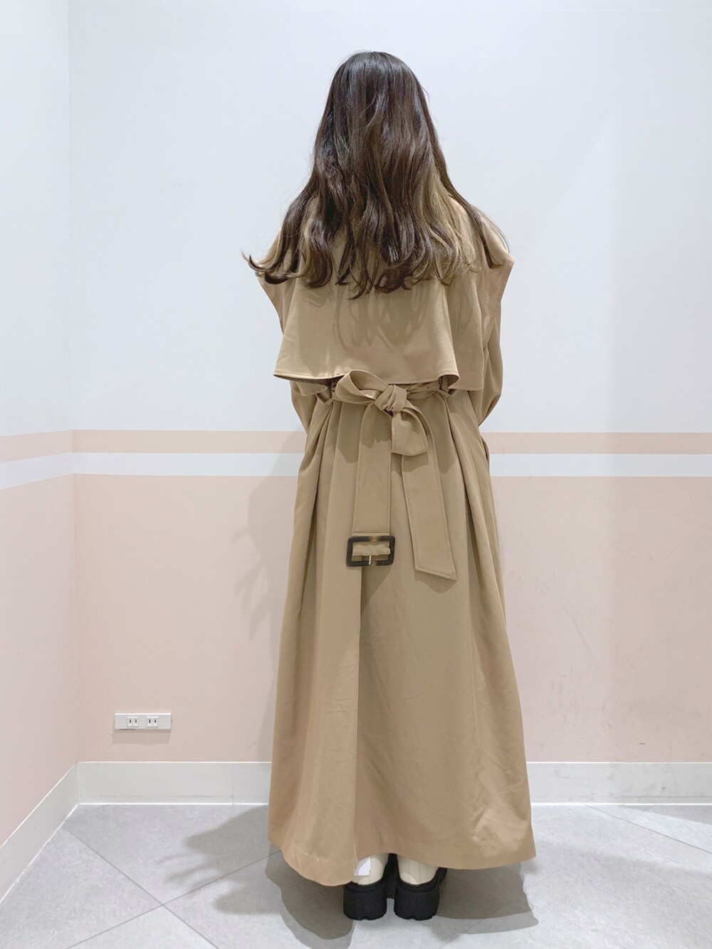 イエロー系のトレンチコート、ブラウン系のボストンバッグ、ホワイト系のブーツを着用したレディースの冬コーディネートの3枚目の写真