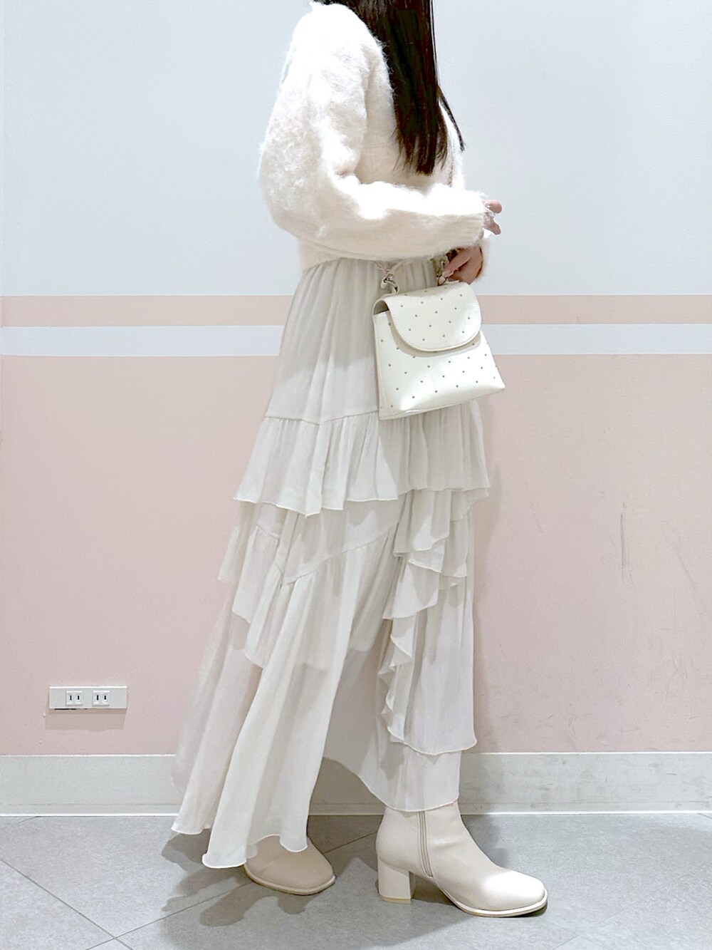 ピンク系のニット/セーター、ホワイト系のスカート、ホワイト系のブーツを着用したレディースの秋コーディネートの2枚目の写真