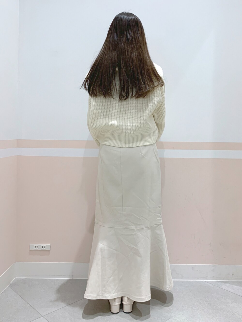 ブラウン系のボストンバッグ、ブラウン系のスカート、ホワイト系のニット/セーターを着用したレディースの冬コーディネートの2枚目の写真