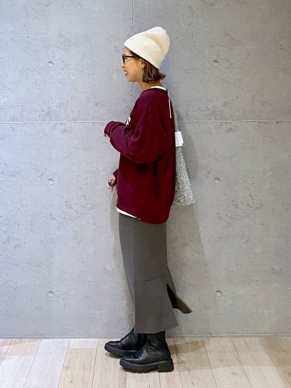 グレー系のスカート、ブラック系のブーツ、レッド系のスウェットを着用したレディースの秋コーディネートの5枚目の写真